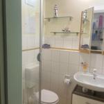 Badezimmer mit Toilette, Waschbecken und Dusche. Wandregale mit Schiffsmotiven.