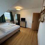 Schlafzimmer mit Bett, Fernseher und Holzboden unter Dachschräge