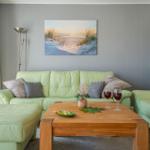 Ein Wohnzimmer mit grünen Sofas, einem Holztisch und einer Wanddekoration.