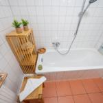 Bad mit Badewanne, Dusche und Holzregal mit Pflanzen.