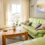 Ein Wohnzimmer mit grünem Sofa, Holztisch und Blick auf Balkon.