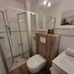 Badezimmer mit Dusche, Toilette und Waschbecken. Wandbild zeigt einen Seehund.