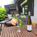 Terrasse mit Liege, Tisch und Wein. Blumen und Snacks auf dem Tisch.