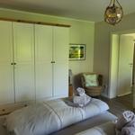 Schlafzimmer mit Doppelbett, Kleiderschrank und Sessel. Decke mit Hängelampe.