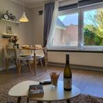 Essbereich mit Tisch, Stühlen und Blick auf Garten. Tisch mit Wein und Buch.