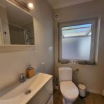Badezimmer mit Waschbecken, Toilette und Fenster mit Tuch.