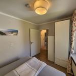 Schlafzimmer mit Bett, Kleiderschrank und Fenster mit Blumenvorhang.