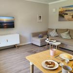Wohnzimmer mit Sofa, TV und Esstisch mit Brötchen.