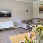 Wohnzimmer mit Sofa, Fernseher und Tisch. Wandbild zeigt Strand.
