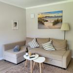 Ein Wohnzimmer mit Sofa, Tisch und Wandbild. Ein Flur führt weiter.