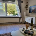 Wohnzimmer mit Fernseher, Tisch, Flur und Fensterblick auf Garten.