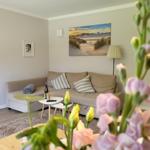 Wohnzimmer mit Sofa, Tisch und Wandbild. Blumen im Vordergrund.