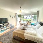 Schlafzimmer mit Doppelbett, Fernseher und Blick auf Balkon.