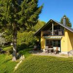 A yellow house with a balcony, garden, and wooden furniture under a blue sky.