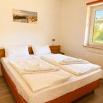 A bedroom with a double bed, window, and wall art.