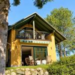 A yellow house with balcony and terrace under trees.