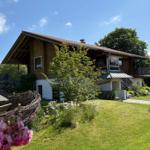 Holzhaus mit Balkon, Garten und blauem Himmel.