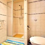 Bath with shower, sink, and toilet. Tiles with decorative stripes.