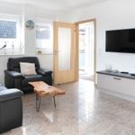 Wohnzimmer mit Ledersofa, Fernseher und Holztisch auf Marmorfliesen