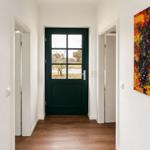 Hausflur mit dunkelgrüner Tür und abstraktem Wandbild in Rot-Orange.