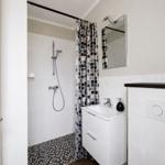 Badezimmer mit Dusche, Waschbecken und Spiegel.