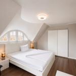 Schlafzimmer mit Dachschräge, Bett, Kleiderschrank und Fenster.