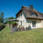 Haus mit Strohdach, Garten und Terrasse mit Sitzgelegenheiten.