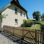 Haus mit Strohdach, Holz-Zaun und Garten mit Terrasse.