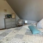 Schlafzimmer mit Dachschrägen, Bett mit gemustertem Bettbezug und Nachttisch.