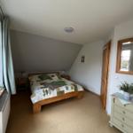 Schlafzimmer mit Holzbett, Nachttischen und Spiegelschrank