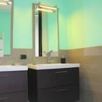Two sinks with mirrors and lighting on green-toned walls.