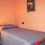A bed with blue bedding and red frame. A poster hangs on the wall.