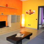 Living room with orange-yellow walls, sofa, coffee table, and TV.