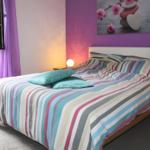 Bedroom with bed, wall art, and window. Purple walls, bed with striped bedding.