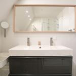 Badezimmer mit Waschbecken, Spiegel und Dusche.