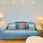 Ein Wohnzimmer mit blauem Sofa, dekorativen Kissen und zwei Stehlampen.
