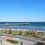 Meerfront mit Steg, Strand und Fahrradweg. Blick von einem Gebäude aus.