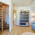 Wohnraum mit Sofa, Bücherregal und spiralförmiger Treppe.