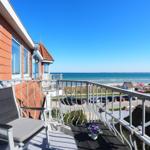 Terrasse mit Sitzgelegenheit und Blick auf das Meer und Strand.