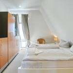 Schlafzimmer mit Doppelbett, Kleiderschrank und Fenster mit Vorhängen.