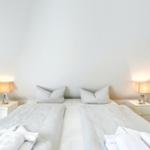 Schlafzimmer mit Doppelbett, zwei Nachttischen und Lampen an den Seiten.