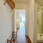 Flur mit Dusche, Garderobe und Blick in Wohnbereich mit Balkon.