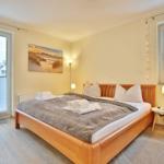 Bedroom with bed, windows, and wall art.