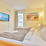 Bedroom with bed, TV, and window. Wall art and floor lamp.