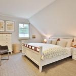 Bedroom with bed, nightstands, and dresser under sloped ceiling