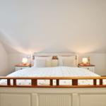 Bedroom with sloped ceiling, bed, nightstands, and window.