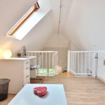A bedroom with sloped ceilings, desk, red cabinet, and window.