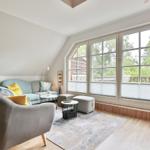 Living room with sofa, armchair, and large windows to the balcony.