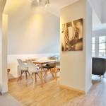 Dining area with table and chairs, wall art, and view of living area with sofa.