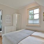 Bedroom with double bed, window, and view into living area with sofa.
